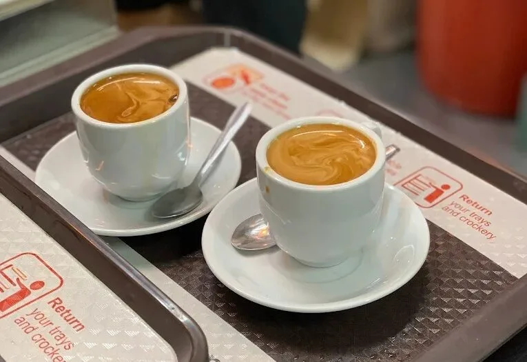 Two cups of hot kopi with chestnut crema on a food-centre tray